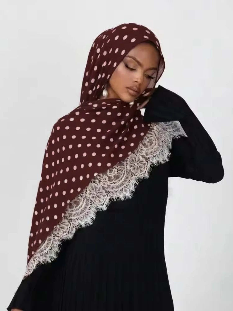 Una mujer vistiendo un hijab de lunares granate con ribete de encaje sobre una blusa negra.