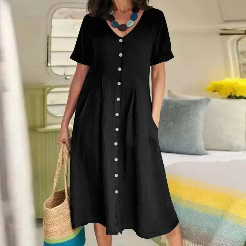Eine Frau in einem eleganten schwarzen Baumwoll- und Hanf-V-Ausschnittkleid in einem hellen Raum.