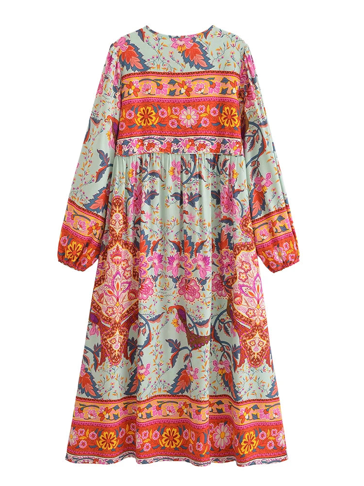 Vestido maxi de manga larga floral con patrones rosa, naranja y verde y flecos decorativos.