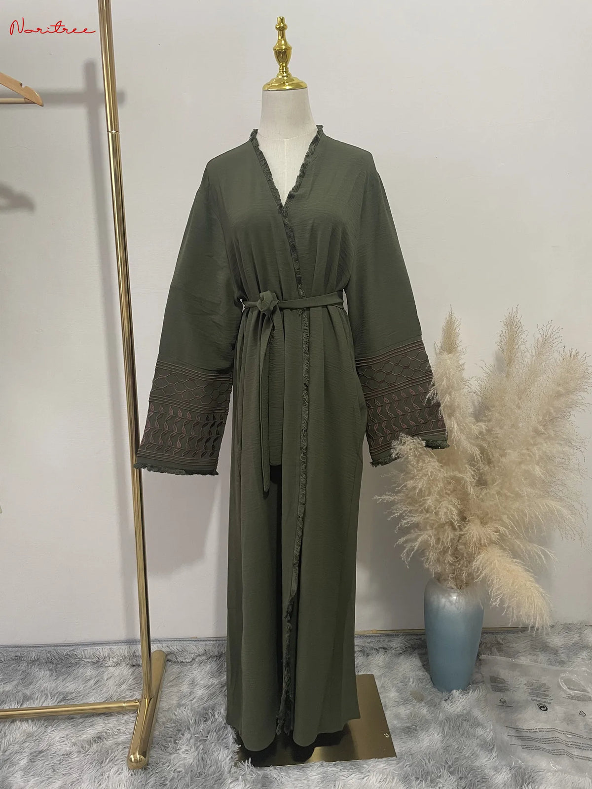 Une longue abaya musulmane brodée vert olive exposée sur un mannequin.