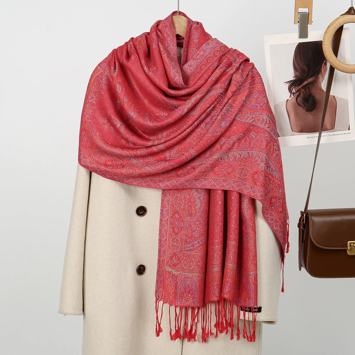 Una vibrante bufanda de bordado de cachemira color coral rojo con estampado paisley, drapeada sobre un abrigo beige.
