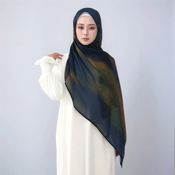 A woman wearing a dark blue watercolor print linen cotton Islamic scarf and a white dress.