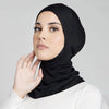 Eine Frau trägt einen schwarzen, dehnbaren Baumwoll-Hijab-Bonnet und blickt direkt in die Kamera.