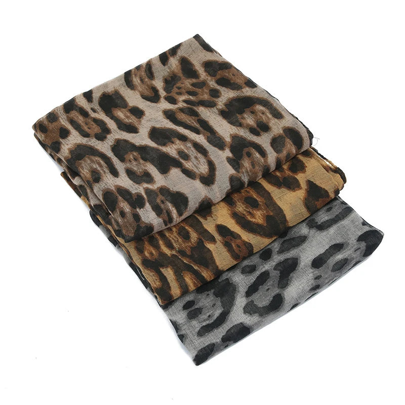 Une pile de châles ou foulards pashmina à imprimé léopard dans diverses nuances de brun et de gris.