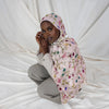 A woman wearing a watercolor printed pink scarf hijab, looking directly at the camera.
