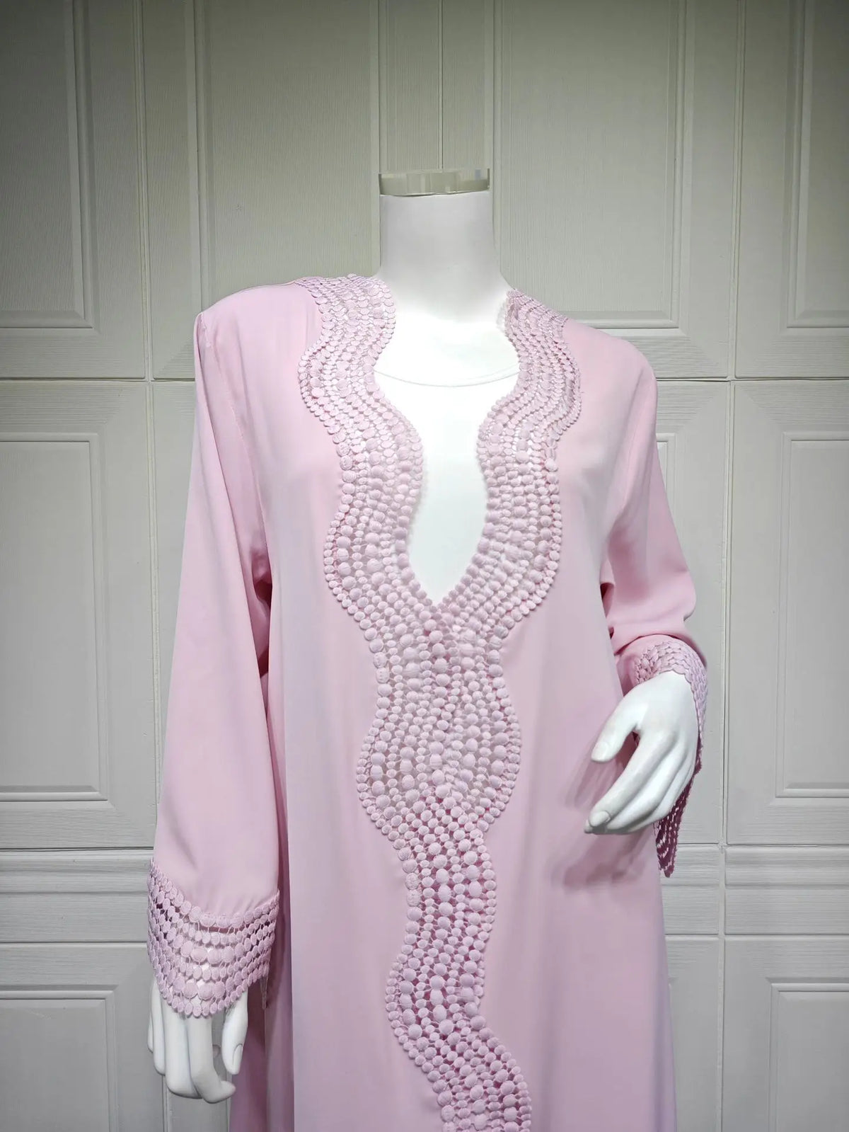 Vestido caftán largo rosa con encaje de ganchillo blanco intrincado en cuello y mangas.