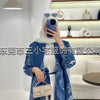 Una mujer vistiendo un cárdigan abaya plisado azul y blanco y hijab, posando en interiores.