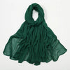 Étole en crêpe de rayon vert émeraude, drapée et pliée sur fond blanc.