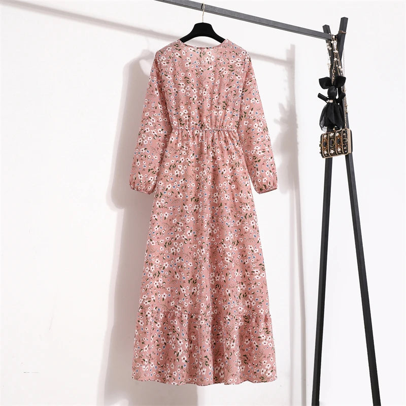 Rosa Boho-Blumenmuster-Maxikleid an einem schwarzen Haken vor weißem Hintergrund