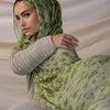 Une femme portant un foulard hijab en polyester doux avec un motif floral vert et blanc.