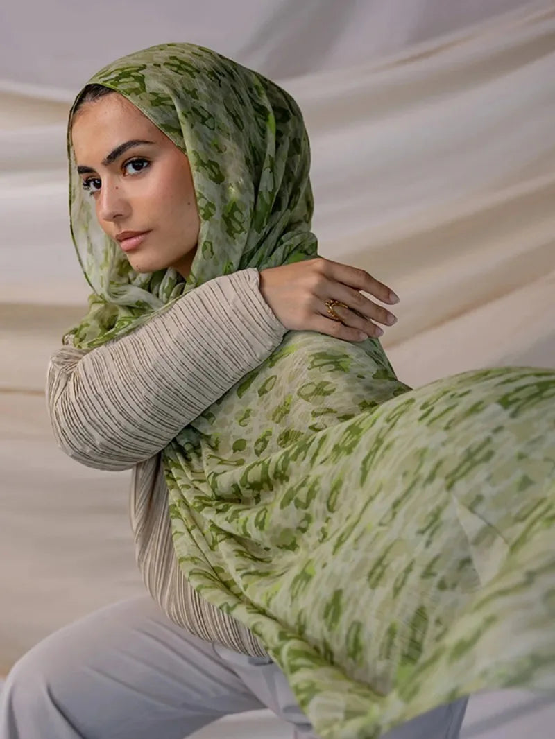 Une femme portant un foulard hijab en polyester doux avec un motif floral vert et blanc.