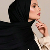 Una mujer vistiendo un pañuelo/hiyab de jersey modal negro premium con una blusa de color crema.