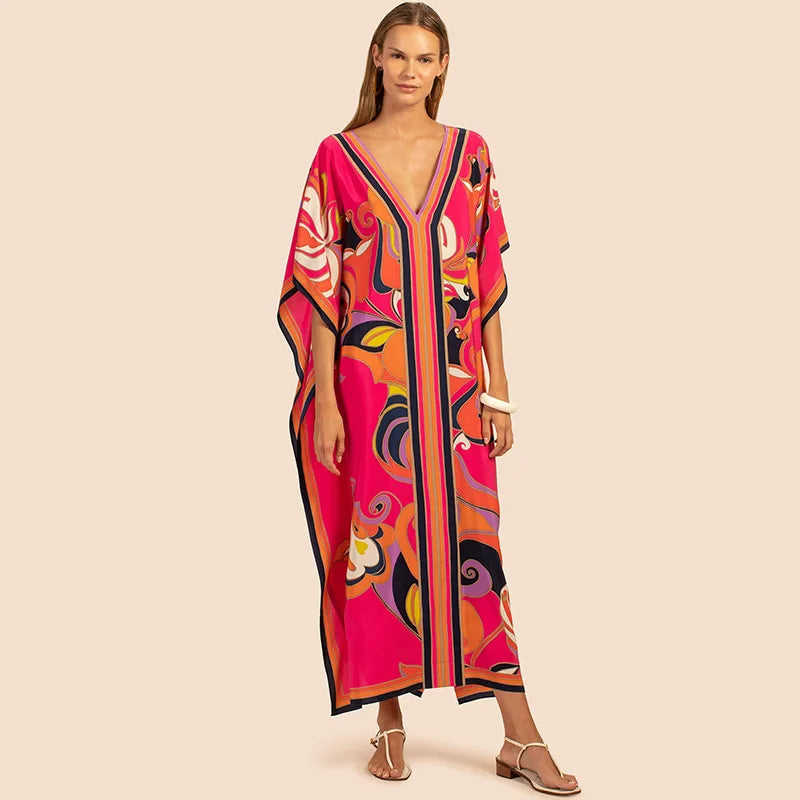 Una mujer modela un vestido caftán bohemio estampado en rosa vibrante y naranja para la playa.