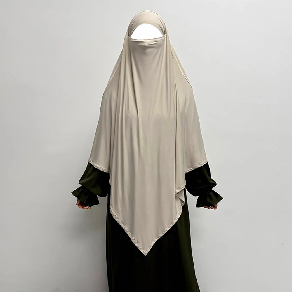 Beige atmungsaktiver Bambus-Jersey-Khimar-Hijab über einem dunkelgrünen Kleidungsstück.
