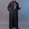 A man wearing a black Moroccan embroidered thobe jellaba with silver detailing.