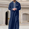 A man wearing a navy blue Moroccan embroidered thobe jellaba with silver trim.