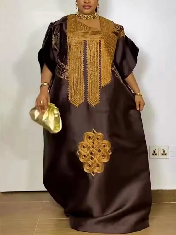 A woman wearing a dark brown traditional Ankara dashiki gown with gold embroidery and jewelry.