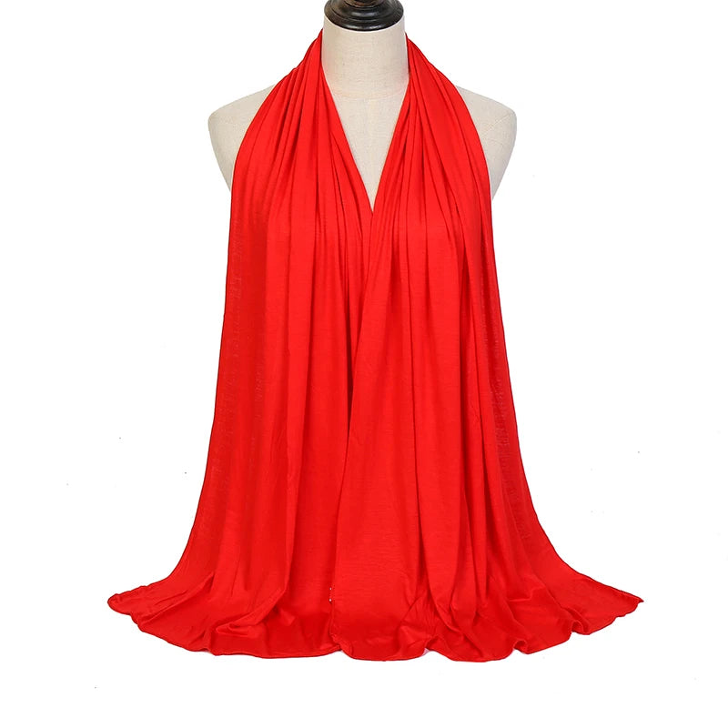 A bright red soft modal jersey hijab scarf draped around a mannequin's neck.
