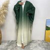 Una mujer vistiendo una elegante bata islámica fluida verde y beige con una blusa blanca.
