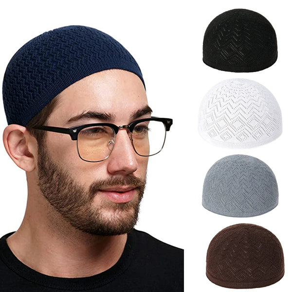 A man wearing a dark blue knit skull cap prayer beanie hat and black eyeglasses, with various colored knit hats displayed bes
