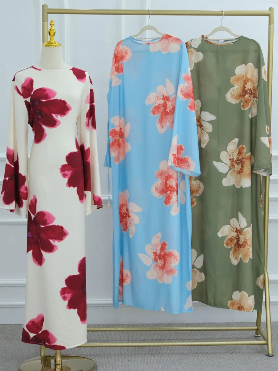 A long, light blue kaftan dress with a floral print displayed on a mannequin.