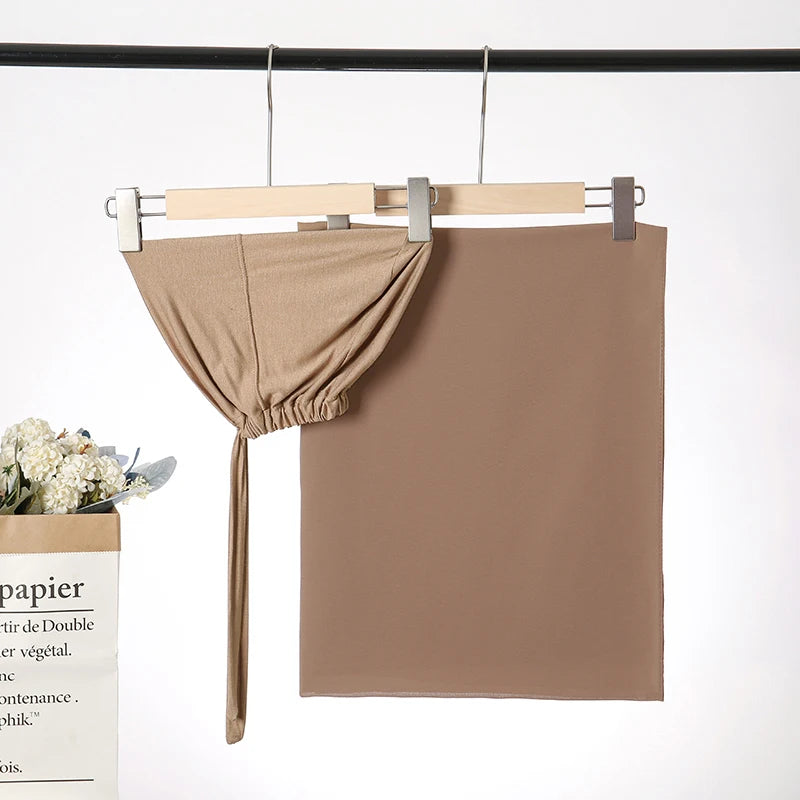 Beige Chiffon-Hijab und Untercap-Set hängt an einem Holzbügel vor weißem Hintergrund.