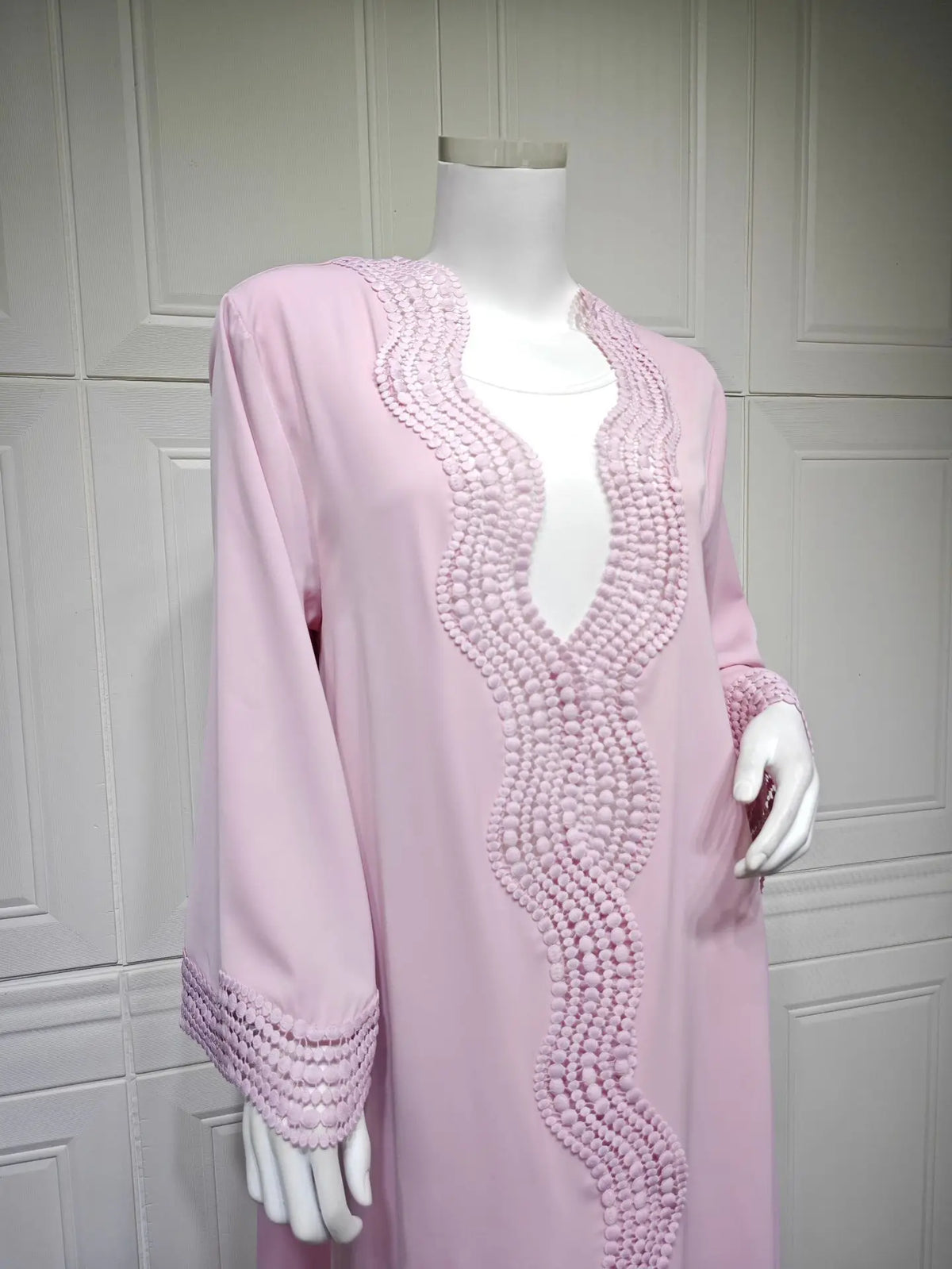 Vestido kaftan largo rosa con intrincados detalles de encaje de ganchillo en cuello y puños.