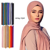 A woman models a soft pink jersey hijab scarf draped around her neck and head.