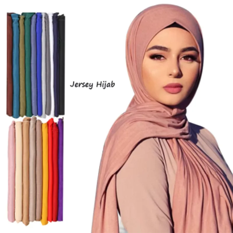 A woman models a soft pink jersey hijab scarf draped around her neck and head.