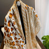 Beige und orange Leopardenmuster-Seide-Schal über einem schwarzen Haken.