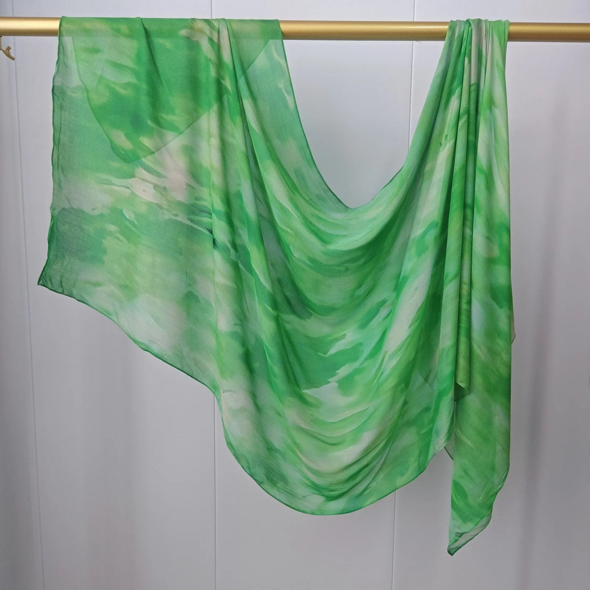 Durchsichtiger grüner und weißer Mehrfarb-Hijab-Schal, drapiert über einem Holzhaken.