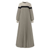 Une longue robe caftan beige à abat-jour vertical et bordure noire sur les épaules.