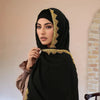 Eine Frau trägt einen schwarzen Spitze-Chiffon-Hijabschal mit goldener Stickerei.