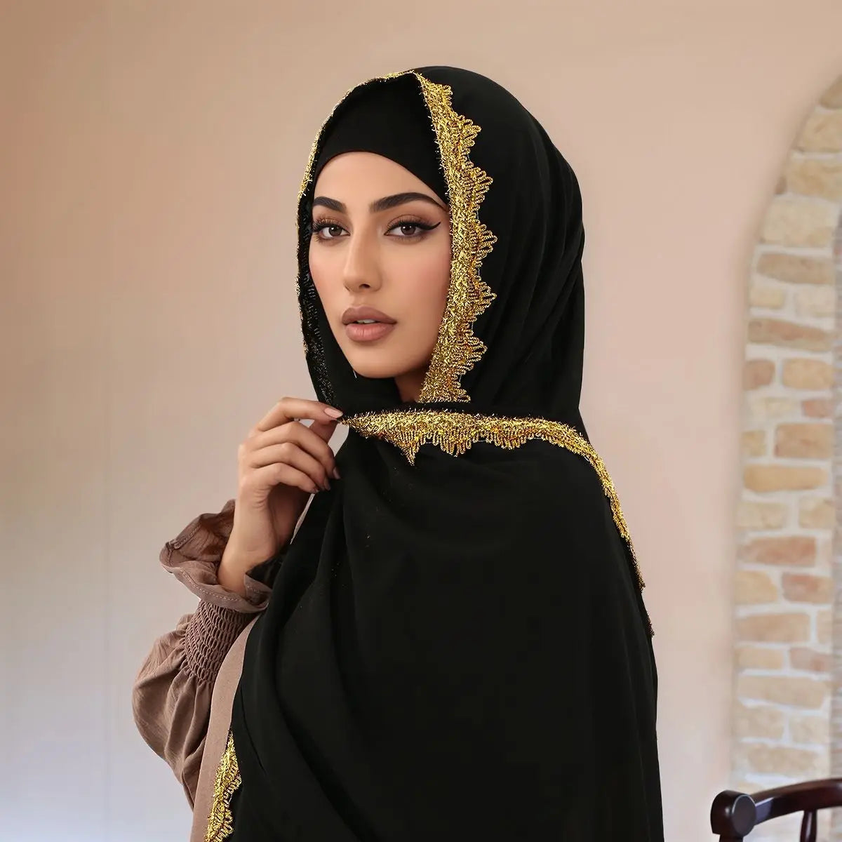 Eine Frau trägt einen schwarzen Spitze-Chiffon-Hijabschal mit Goldstickerei.