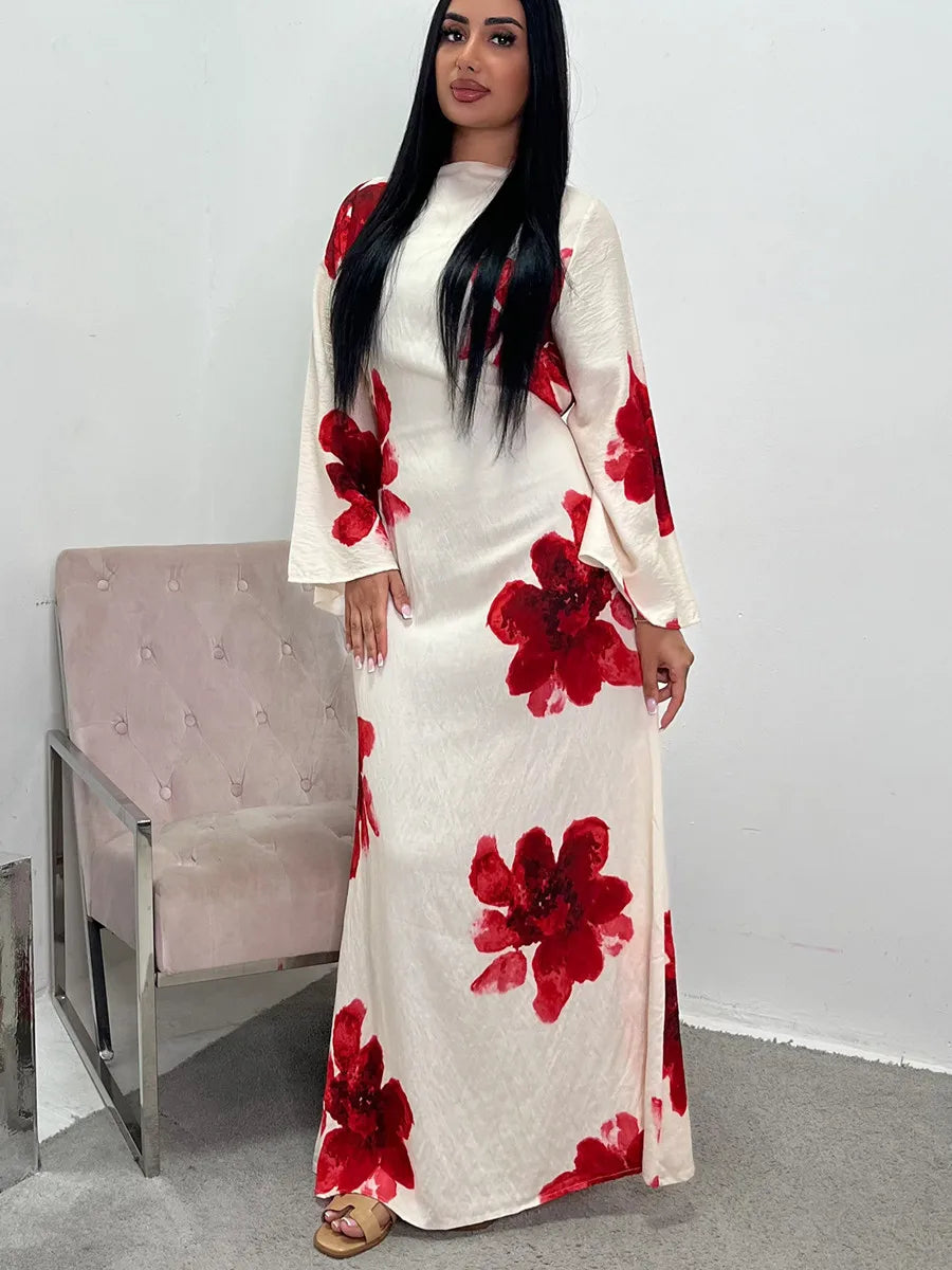 A woman models a white kaftan dress with a red floral print and black hair against a light background.