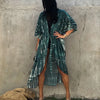 Eine Frau in einem blau-weißen gestreiften Sommer-Kimono-Überkleid vor einer Betonwand.