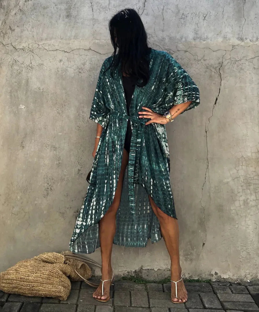 Eine Frau in einem blau-weißen gestreiften Sommer-Kimono-Überkleid vor einer Betonwand.