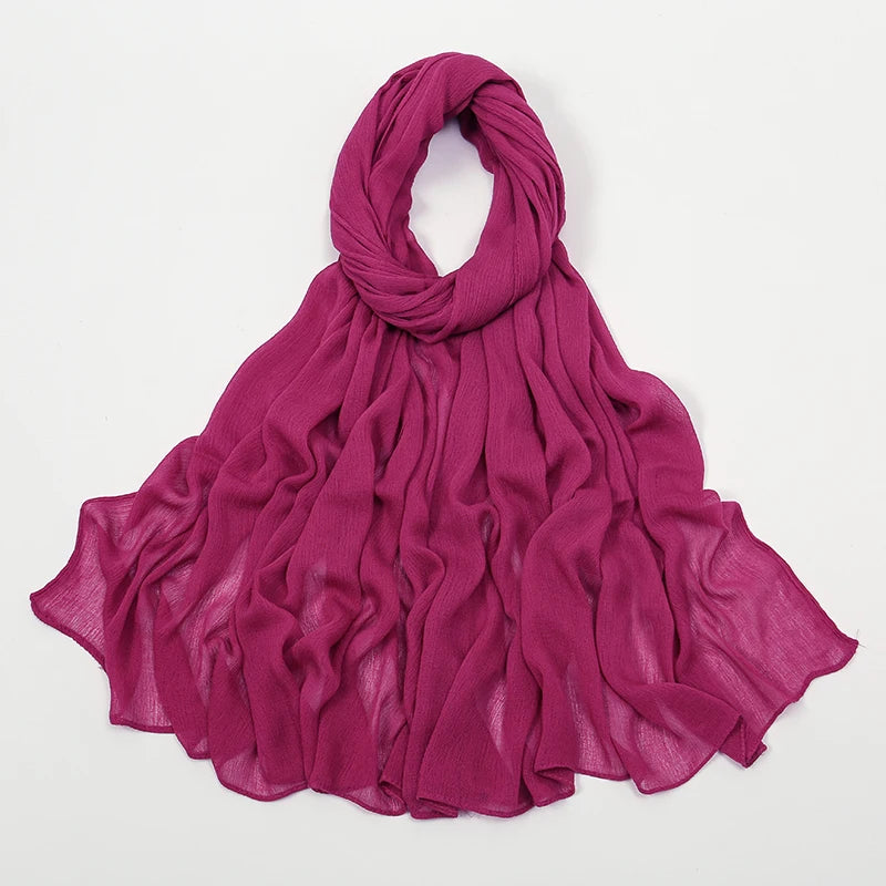 Étoffe crinkle magenta vibrante, foulard/châle drapé autour du cou et flottant.