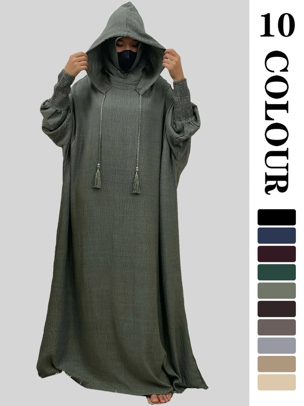 A model wearing a multi-color abaya with a hood and batwing sleeves in a muted olive green color.