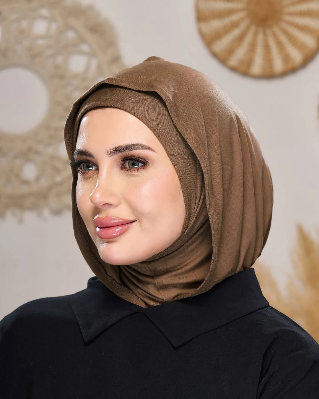 Eine Frau trägt einen einfarbigen braunen Jersey-Hijab und ein schwarzes Hemd mit Kragen.