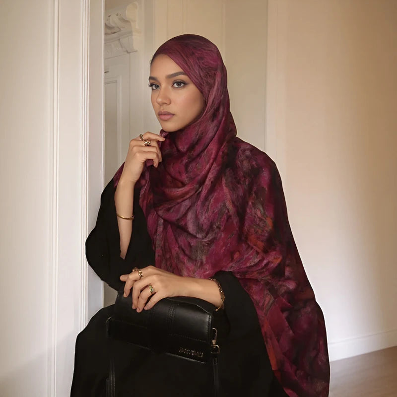 Eine Frau trägt einen tiefvioletten Aquarell-Blumenmuster-Hijab und schwarze Kleidung.
