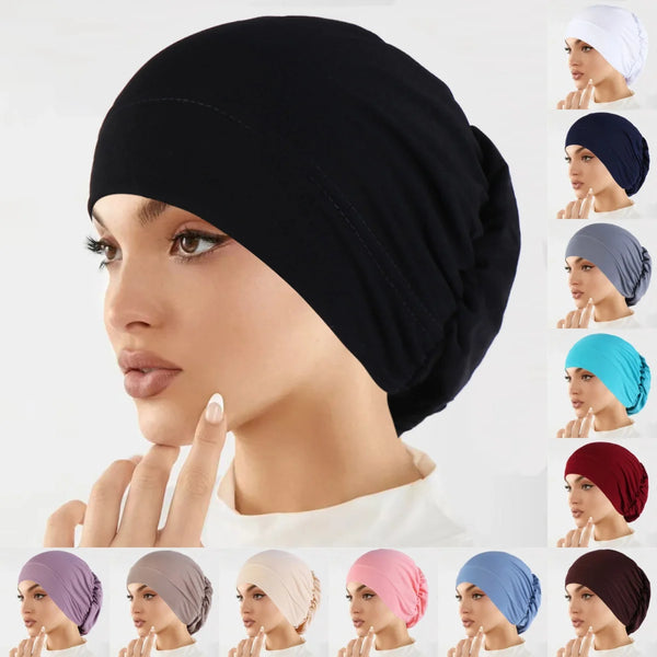 A close-up of a woman modeling various colored stretch turban caps on her head.