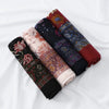 Stapel von floral bedruckten Voile-Hijabs in erdigen Tönen wie Rot, Bordeaux und Dunkelblau.