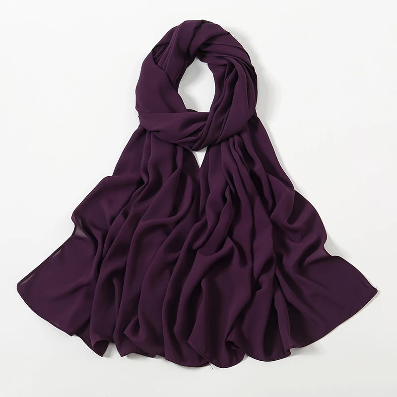 Ein drapiertes, tiefviolettes Chiffon-Hijab-Schal, gefaltet und vor weißem Hintergrund präsentiert.