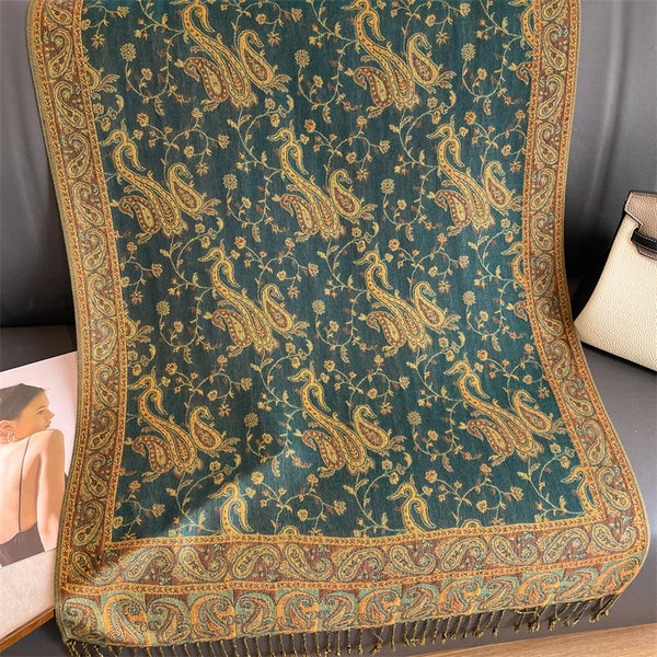 A dark teal luxury pashmina hijab scarf featuring intricate gold floral embroidery and tasseled edges.