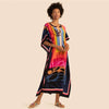 Una mujer modela un vestido caftán bohemio estampado colorido en tonos rosa, naranja y azul.