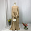 Beige elegante Batwing-Abaya mit Goldschmuck und floralen Akzenten auf einem Mannequin.