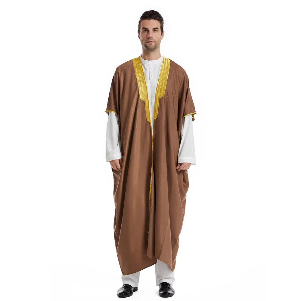 Ein Mann trägt einen braunen Jubba-Kaftan mit gelbem Zierrand über einem weißen Hemd.