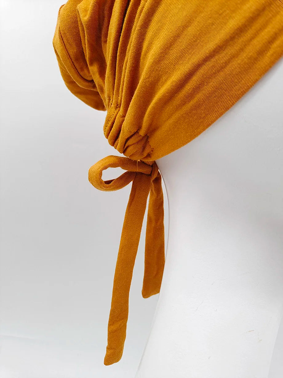 Pañuelo elegante turbante modal amarillo mostaza atado con un lazo de tela.