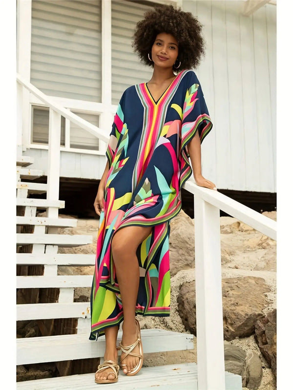 A woman wearing a colorful Moroccan batwing kaftan cover-up dress standing on a wooden deck.
